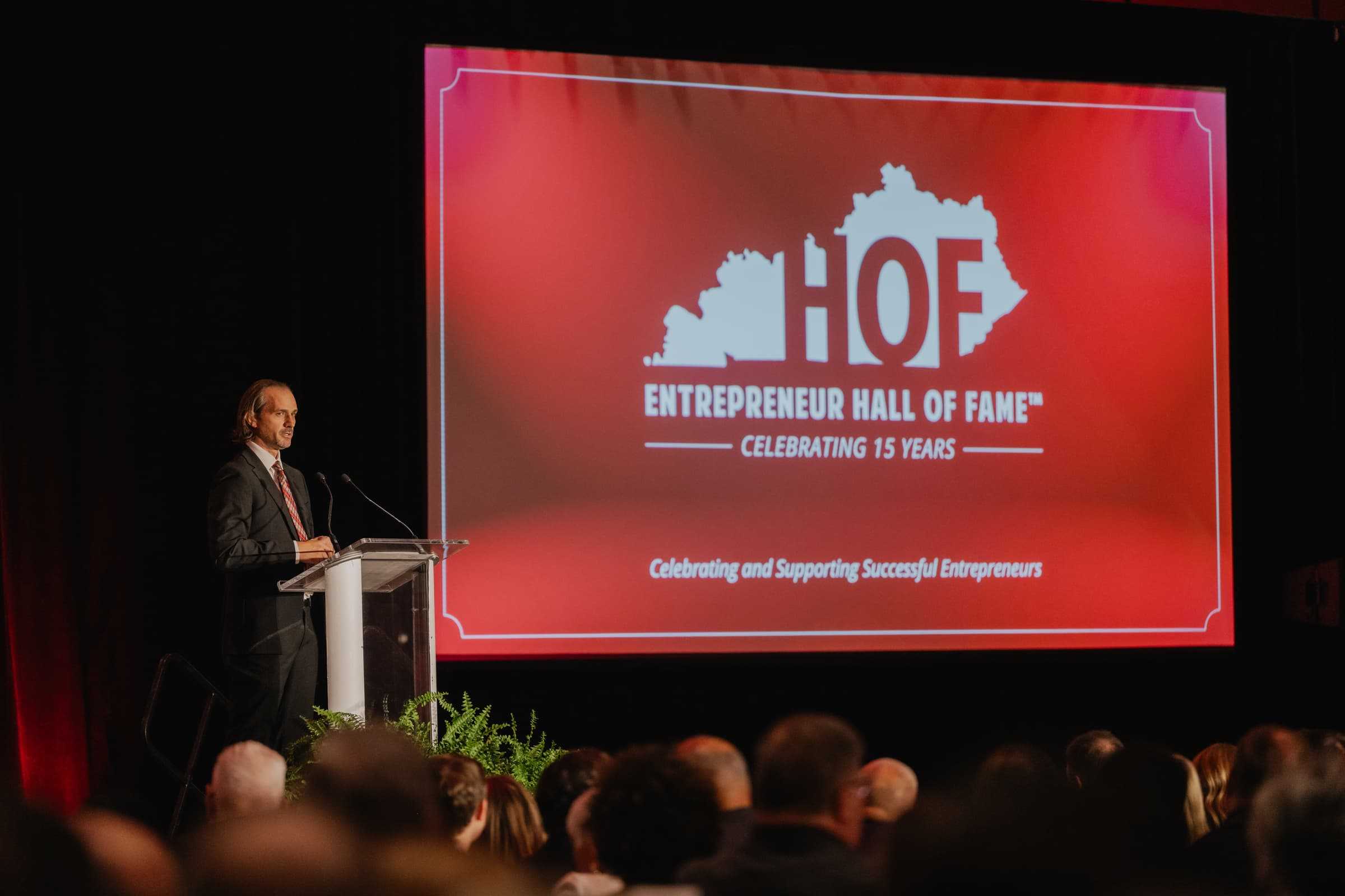 Speaker at the podium beside the Hall of Fame presentation screen